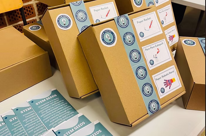 STEMKit boxes labeled with Paper Rocket, Pom-Pom Catapult, and Paper Robotic Hand experiment cards