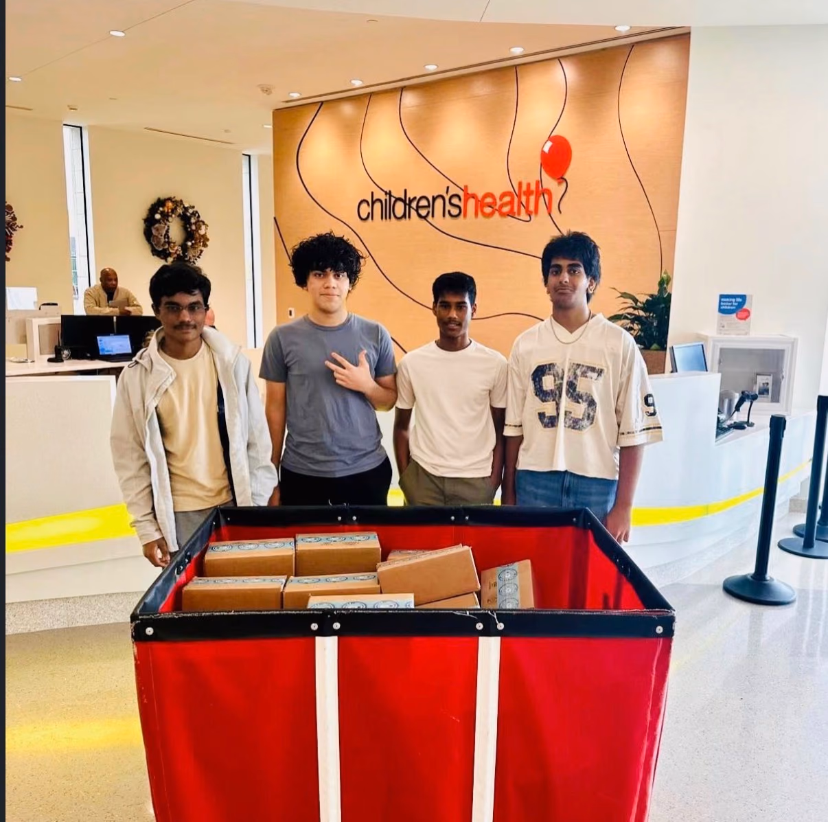 Four chapter members standing behind a cart of STEMKits in the Children's Health lobby