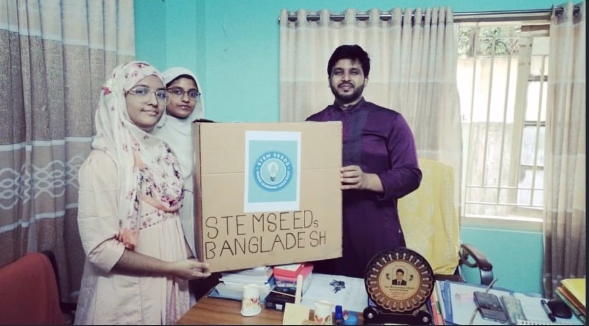 Chapter members and a school representative holding a STEMSeeds Bangladesh box