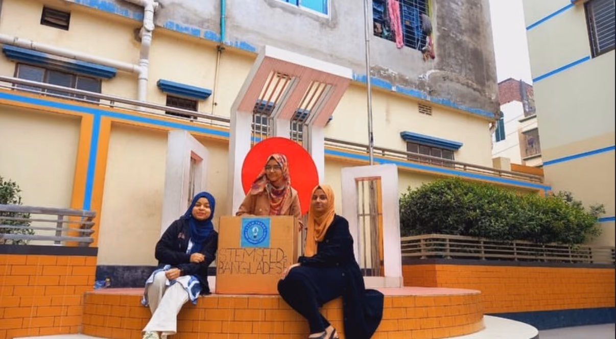 Three chapter members sitting beside a STEMSeeds Bangladesh box in the school courtyard