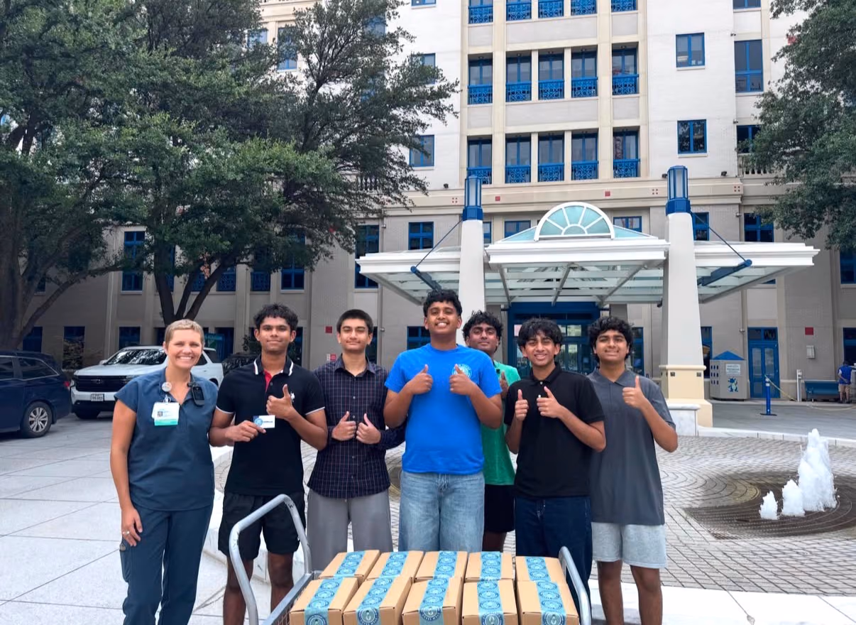 Reedy chapter members giving a thumbs up with a Cook Children's staff member and a cart of STEMKits outside the hospital