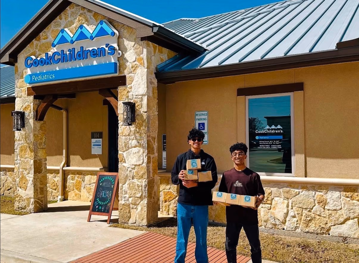 Two STEMSeeds members holding STEMKits outside Cook Children's Pediatrics