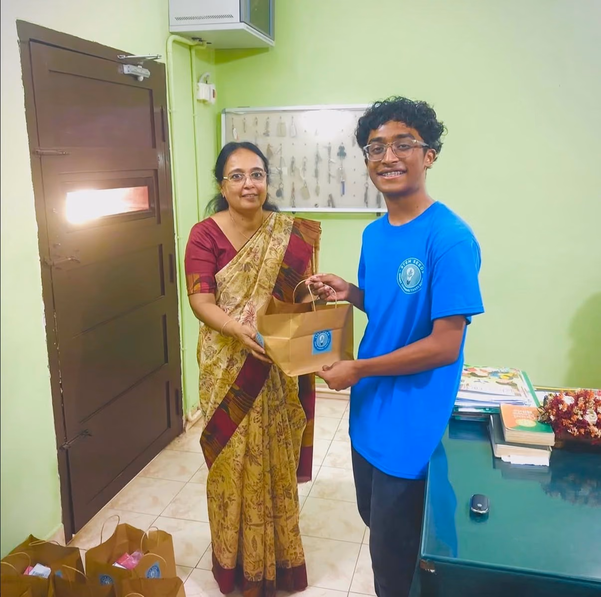 A STEMSeeds member handing a STEMKit bag to principal Anita Susan Varghese