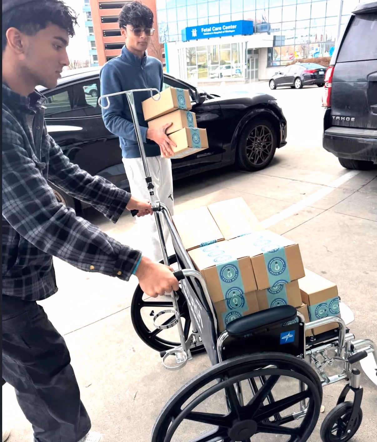 Two chapter members wheeling STEMKit boxes toward the Children's Hospital of Michigan
