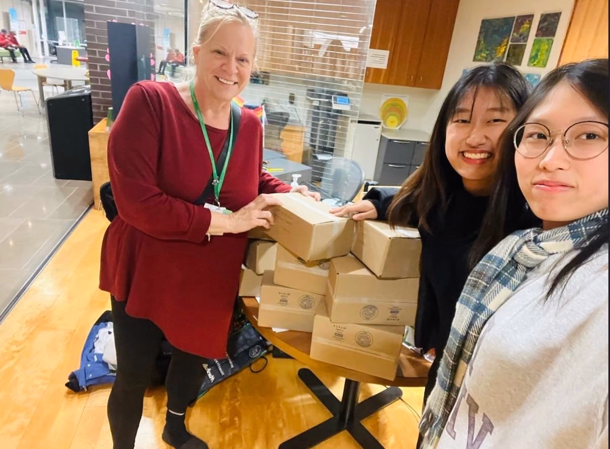 Two chapter members and a Holland Bloorview staff member with a stack of STEMKit boxes
