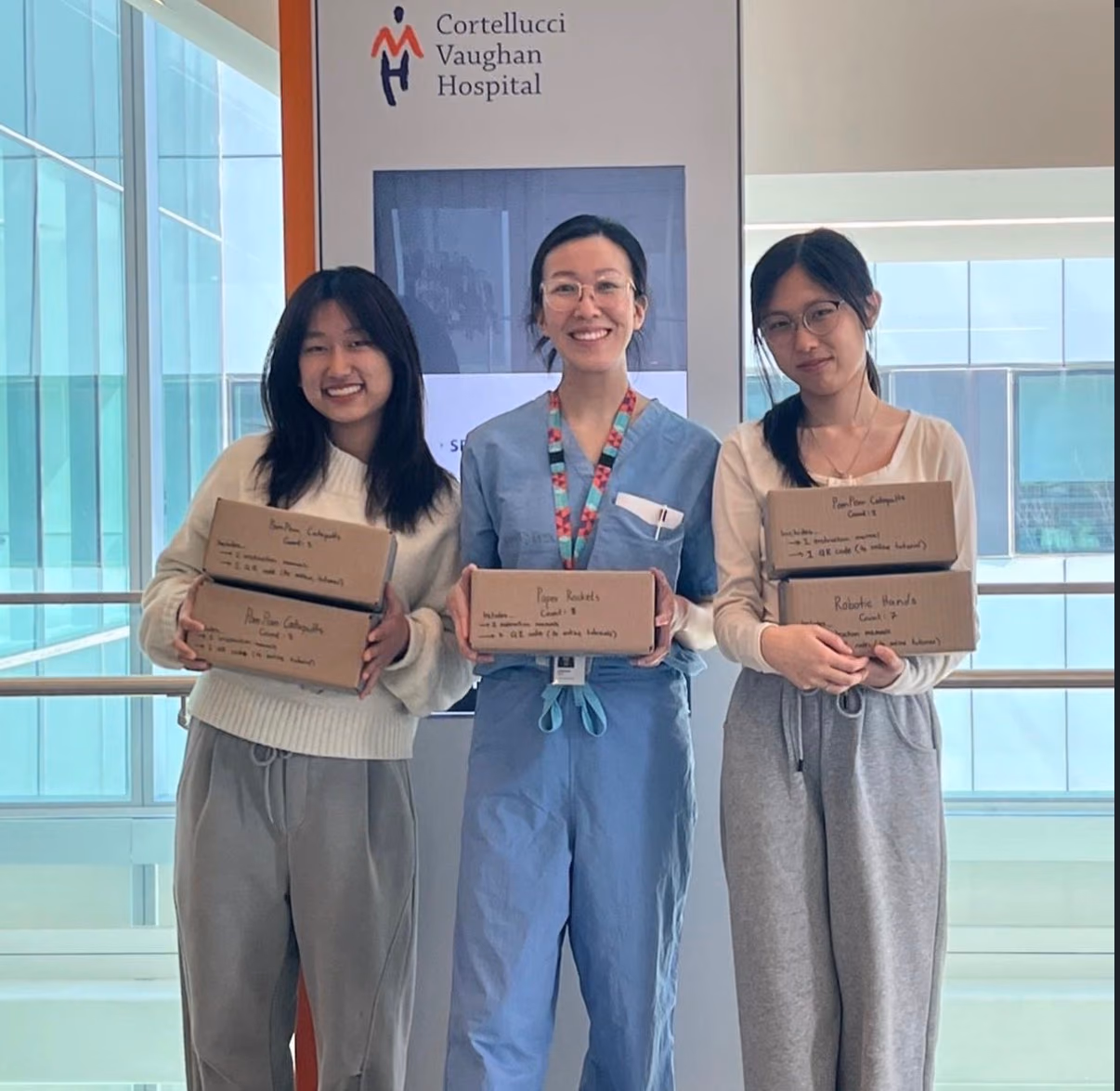 Two chapter members and a hospital staff member holding boxes of STEMKits at Cortellucci Vaughan Hospital