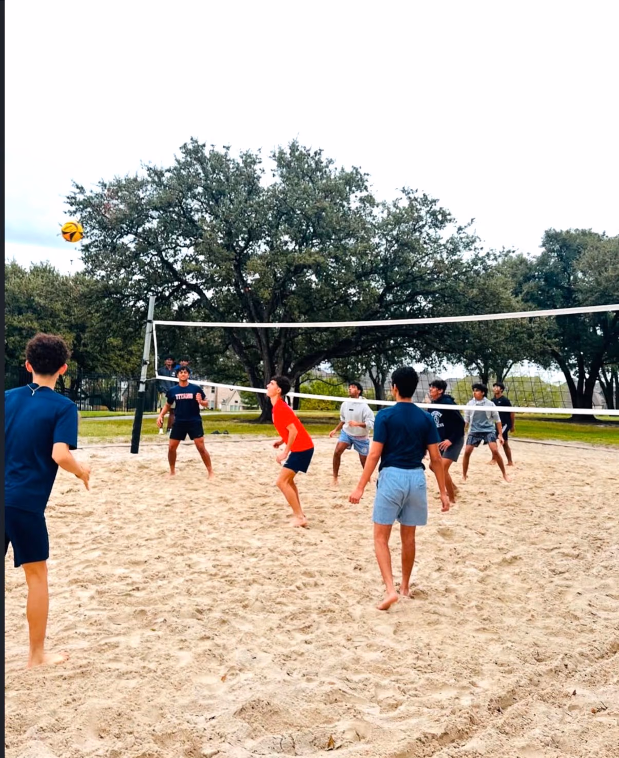 Players in the middle of a rally on the sand volleyball court
