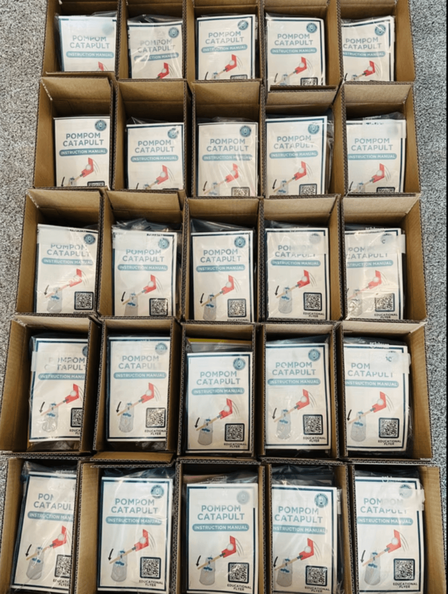 Boxes of kits packed with PomPom Catapult instruction manuals